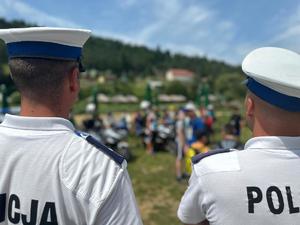 Dwóch policjantów odwróconych tyłem w tle uczestnicy spotkania.