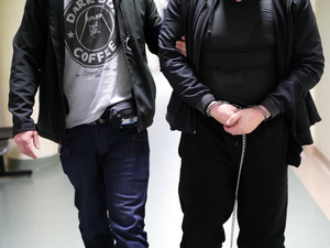 policjant z zatrzymanym zakutym w kajdanki