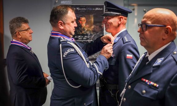 policjant przypina odznaczenie innemu policjantowi