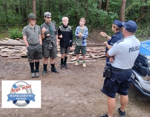 Para policjantów rozmawia z grupą młodych harcerzy.
