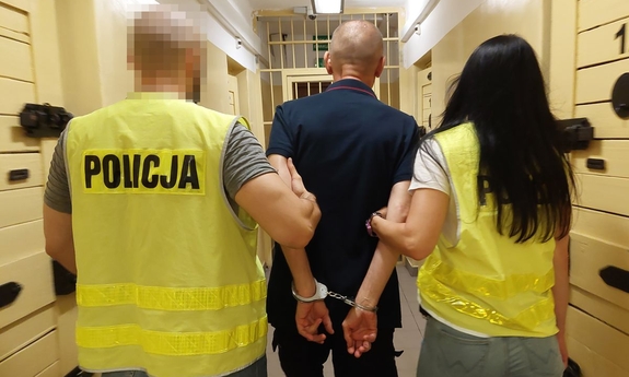 na zdjęciu funkcjonariusze prowadzą zatrzymanego mężczyznę