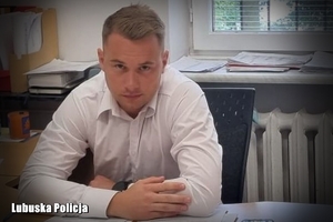 na zdjęciu policjant siedzi przy biurku