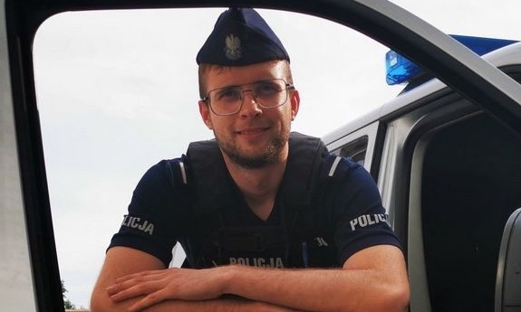 policjant umundurowany patrzy przez okno w otwartych drzwiach radiowozu