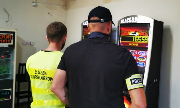dwaj funkcjonariusze stoją w nielegalnym salonie gier hazardowych