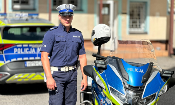Starszy sierżant Patryk Piechowski stoi przy motocyklu policyjnym