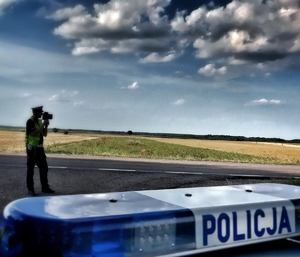 funkcjonariusz ruchu drogowego na drodze w trakcie mierzenia prędkości pojazdów