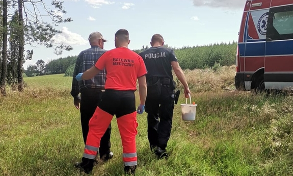 na zdjęciu policjant i ratownik pogotowia ratunkowego prowadzą odnalezionego mężczyznę do karetki
