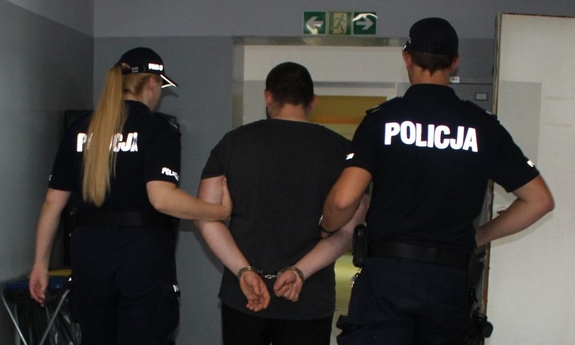 umundurowani policjanci prowadzą zatrzymanego
