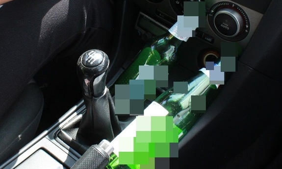 butelka alkoholu leży w samochodzie przy dźwigni zmiany biegów