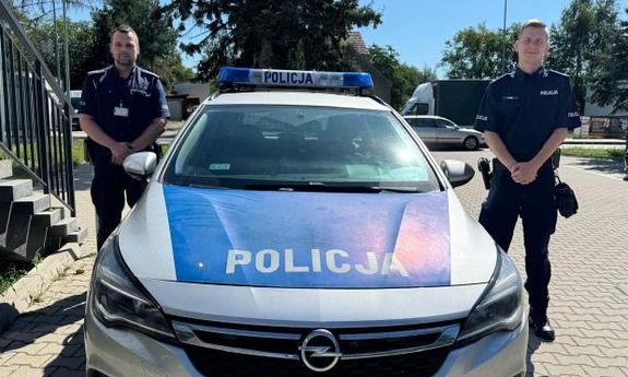 dwóch policjantów stoi przy radiowozie