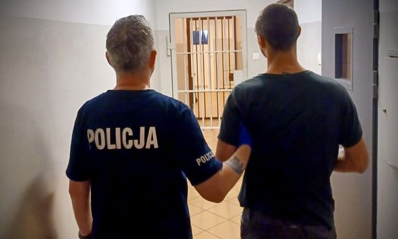 policjant prowadzi zatrzymanego