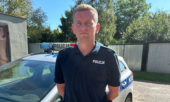 policjant stoi przy radiowozie