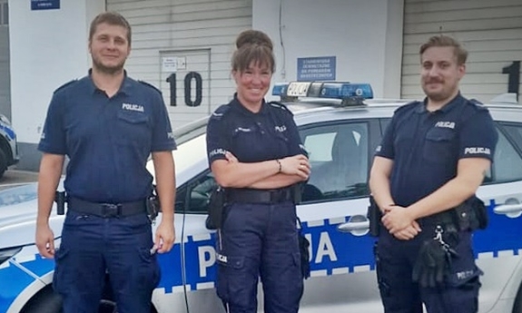 Troje policjantów, którzy udzielili pomocy kobiecie stoją przy radiowozie