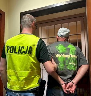 policjant z zatrzymanym mężczyzną zakutym w kajdanki