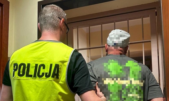 policjant z zatrzymanym mężczyzną zakutym w kajdanki