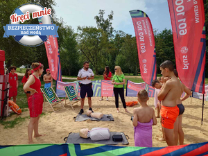 Policjant na plaży z uczestnikami spotkania.