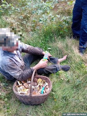 Odnaleziony mężczyzna siedzi na trawie, obok niego kosz z grzybami
