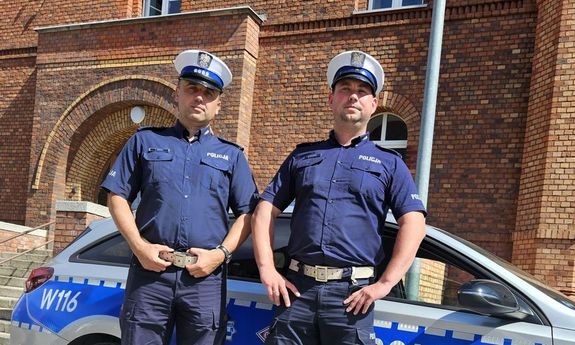 policjanci stoją przy radiowozie