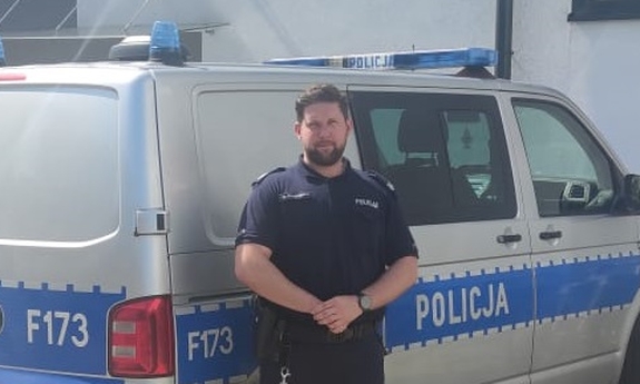 Policjant stoi przy radiowozie