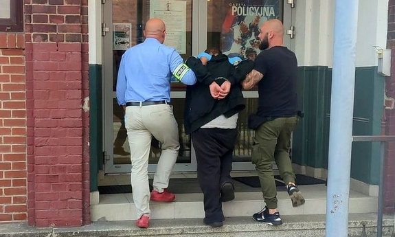 dwaj funkcjonariusze wprowadzają do budynku komisariatu Policji zatrzymanego