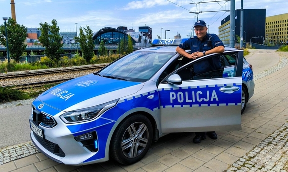 na zdjęciu umundurowany policjant stoi przy radiowozie