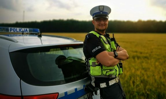 policjant stoi przed radiowozem