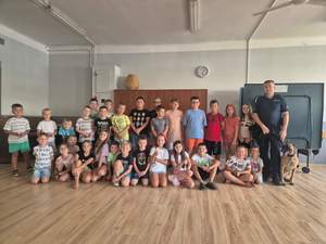 Policjant pozuje do zdjęcia z grupą dzieci.