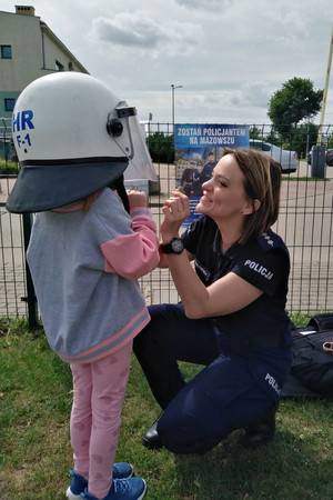 Policjantka zakłada dziecku kask wykorzystywany przez policjantów.
