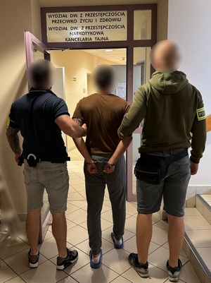 policjanci prowadzą zatrzymanego