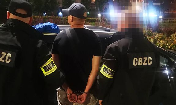 POLICJANCI STOJĄ Z ZATRZYMANYM