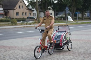 strażak jedzie rowerem z przyczepką