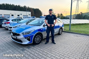 policjant stoi przed radiowozem