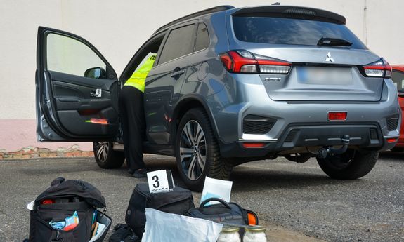ODZYSKANY samochód, do środka zagląda policjant, na zewnątrz leżą torby