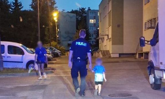 Policjant idzie z 4 latkiem za rączkę po osiedlu