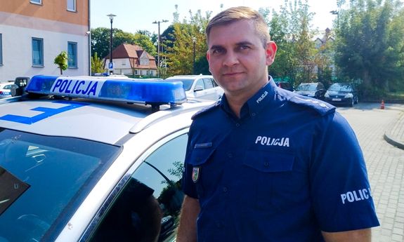 policjant stoi przy radiowozie