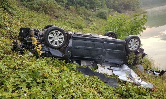 na zdjęciu przewrócone auto, w tle jezioro