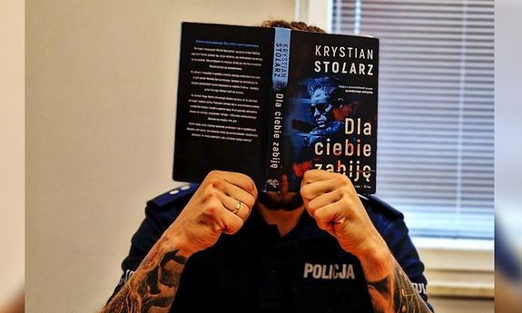 twarz policjanta zasłania okładka jego książki