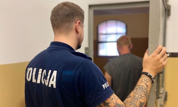 policjant zamyka w celi zatrzymanego