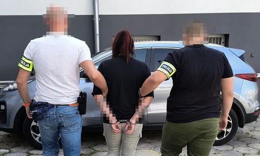 policjanci prowadzą zatrzymaną kobietę