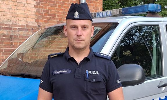 policjant stoi przed radiowozem