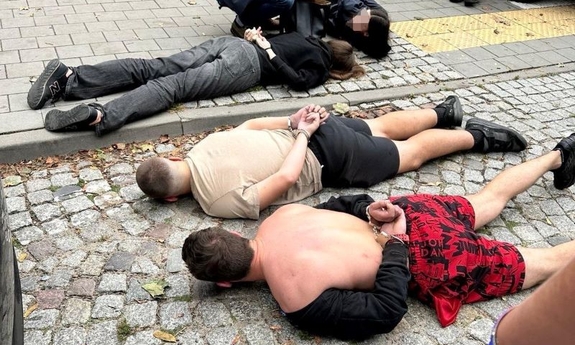 zatrzymani w kajdankach leżą na ziemi