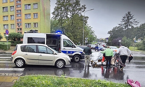 wypadek drogowy - samochód osobowy na pasach obok radiowóz policyjny i karetka, na ulicy leżą osoby przykrywane przez inne kocami ratunkowymi