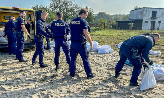Policjanci pakują worki z piaskiem do busa