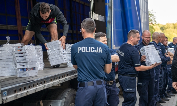 policjanci w trakcie pakowania na ciężarówkę darów dla powodzian
