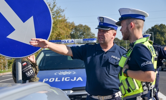 dwaj policjanci ruchu drogowego przy radiowozie