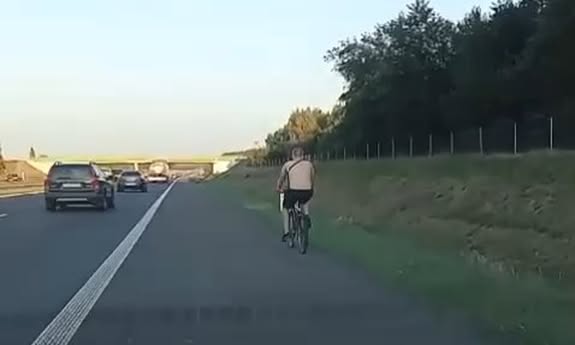 KADR Z KANERY SANOCHODOWEJ, CYKLISTA JEDZIE PO PASIE AWARYJNYM