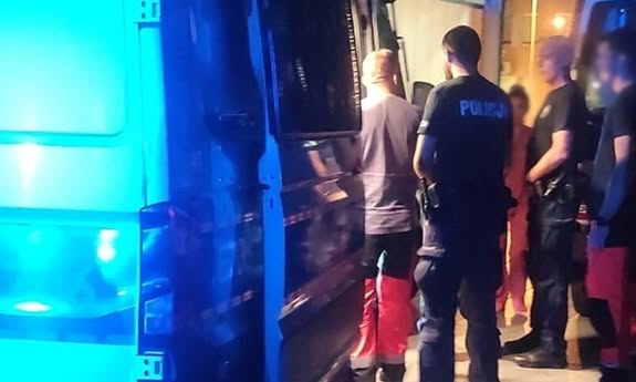 bus radiowóz przed szpitalem, obok drzwi stoją ratownicy i policjanci