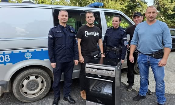 policjanci stoją przy radiowozie i kuchence gazowej