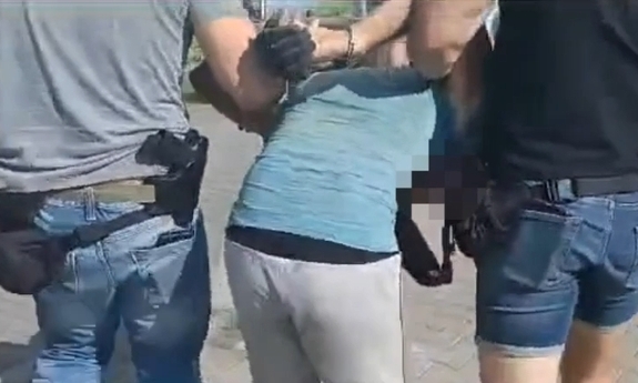 dwaj policjanci prowadza zatrzymanego zakutego w kajdanki