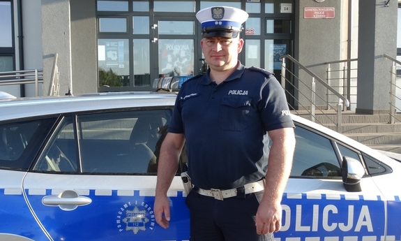 policjant stoi przy radiowozie